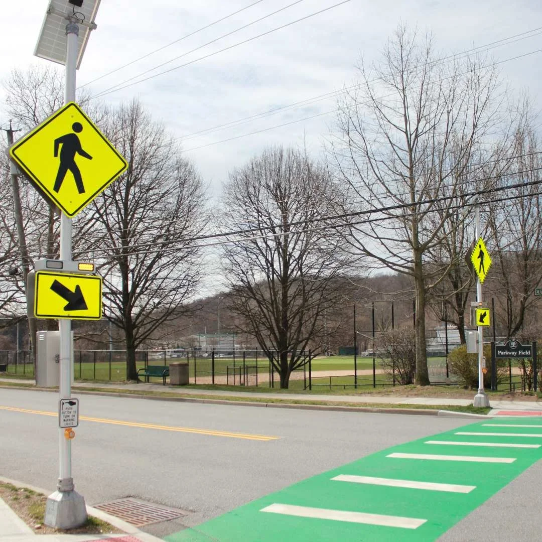 A crosswalk on a street, accompanied by a sign that reads "walk," promoting safe pedestrian crossing.