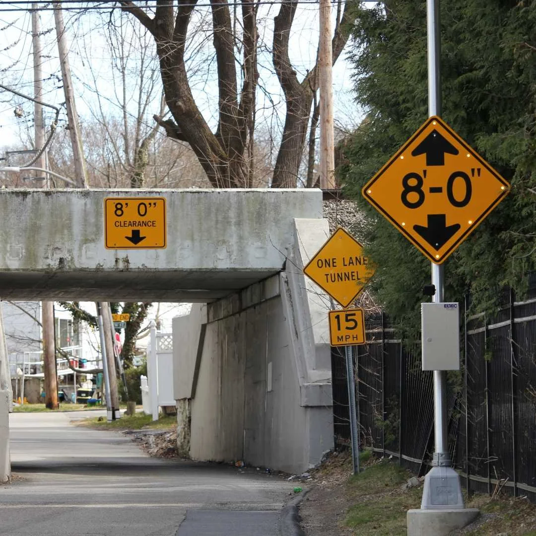 A yellow directional sign with a striking black arrow, guiding the viewer's attention to the 8ft clearance