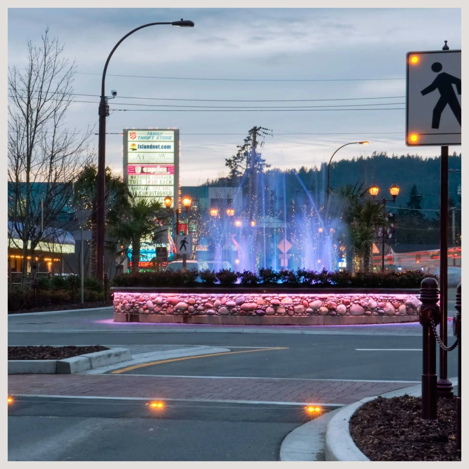 A fountain situated in the center of a street, accompanied by a traffic light and an In-Road Warning Light System.