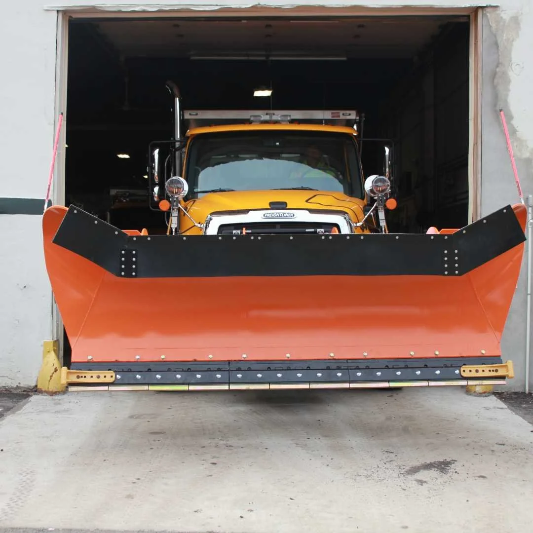A large yellow snow plow stands ready for winter, showcasing its robust design and bright color 