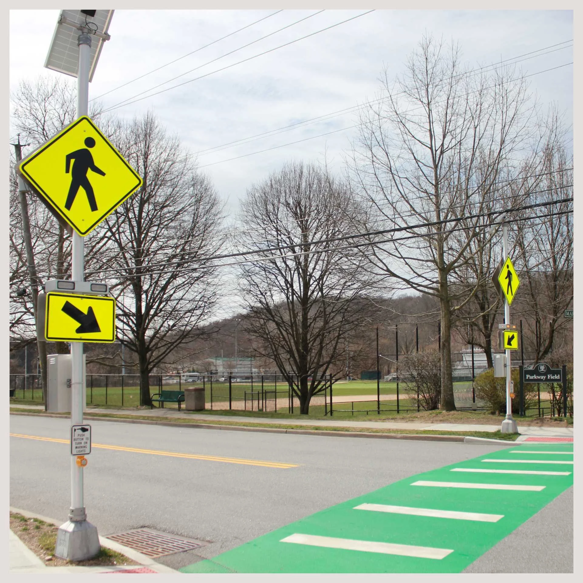 A street scene featuring a crosswalk and a "walk" sign, enhanced by Rectangular Rapid Flashing Beacon Systems for safety.