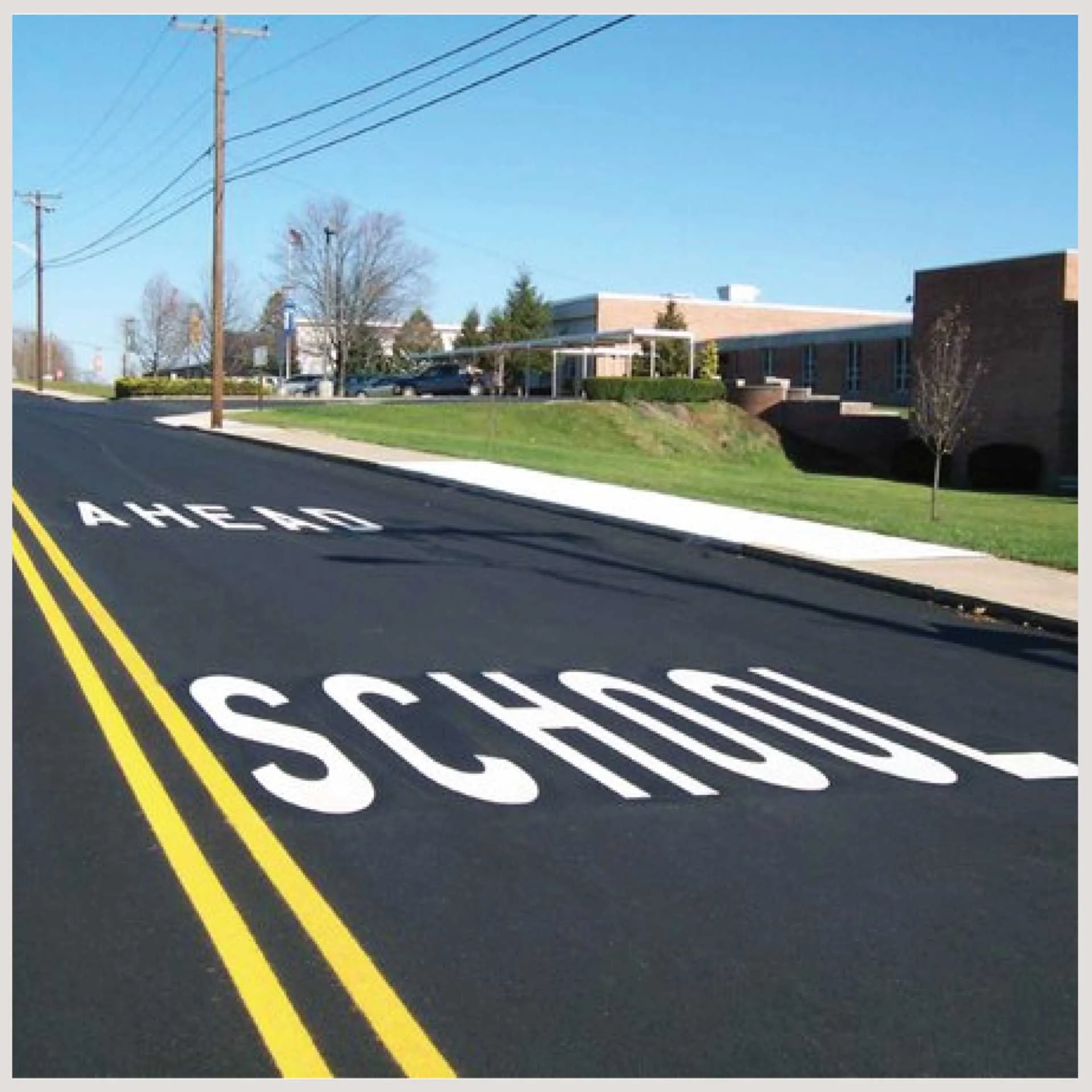 A road featuring the word "school ahead" prominently painted on its surface, indicating a nearby educational institution.