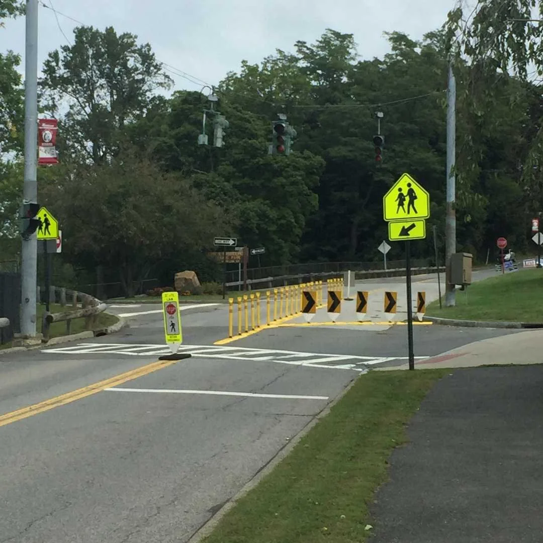 A street scene featuring the impact recovery system, surrounded by buildings and greenery, under a clear blue sky.